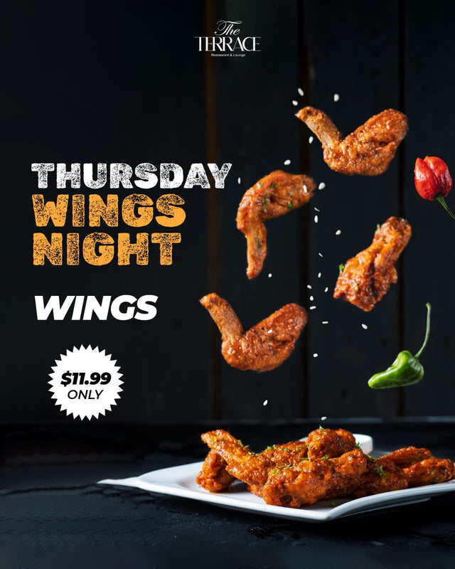 A plate of house wings tossed in sauce, with chillies and sesame